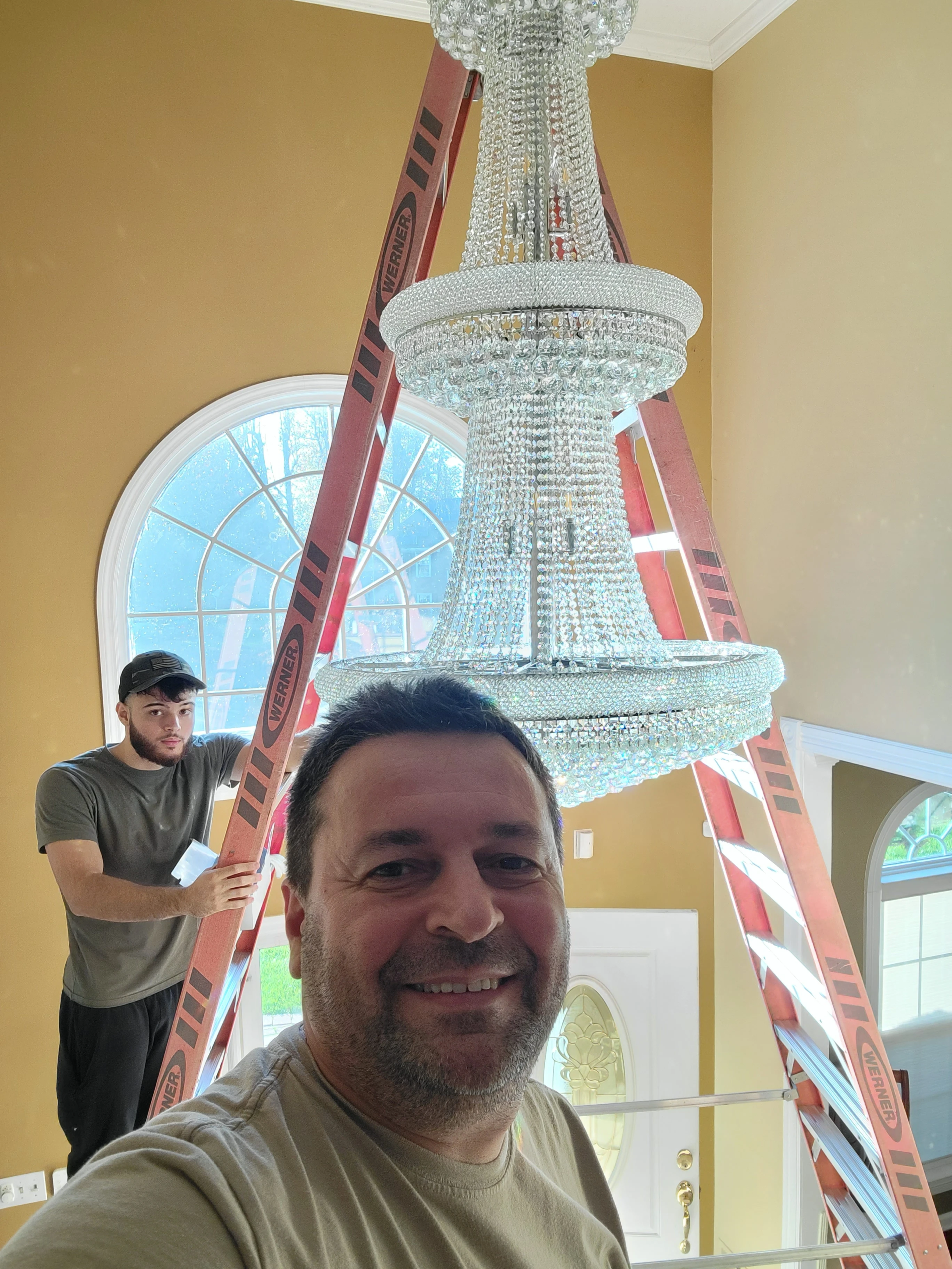 Two Art Power team members together during a chandelier installation