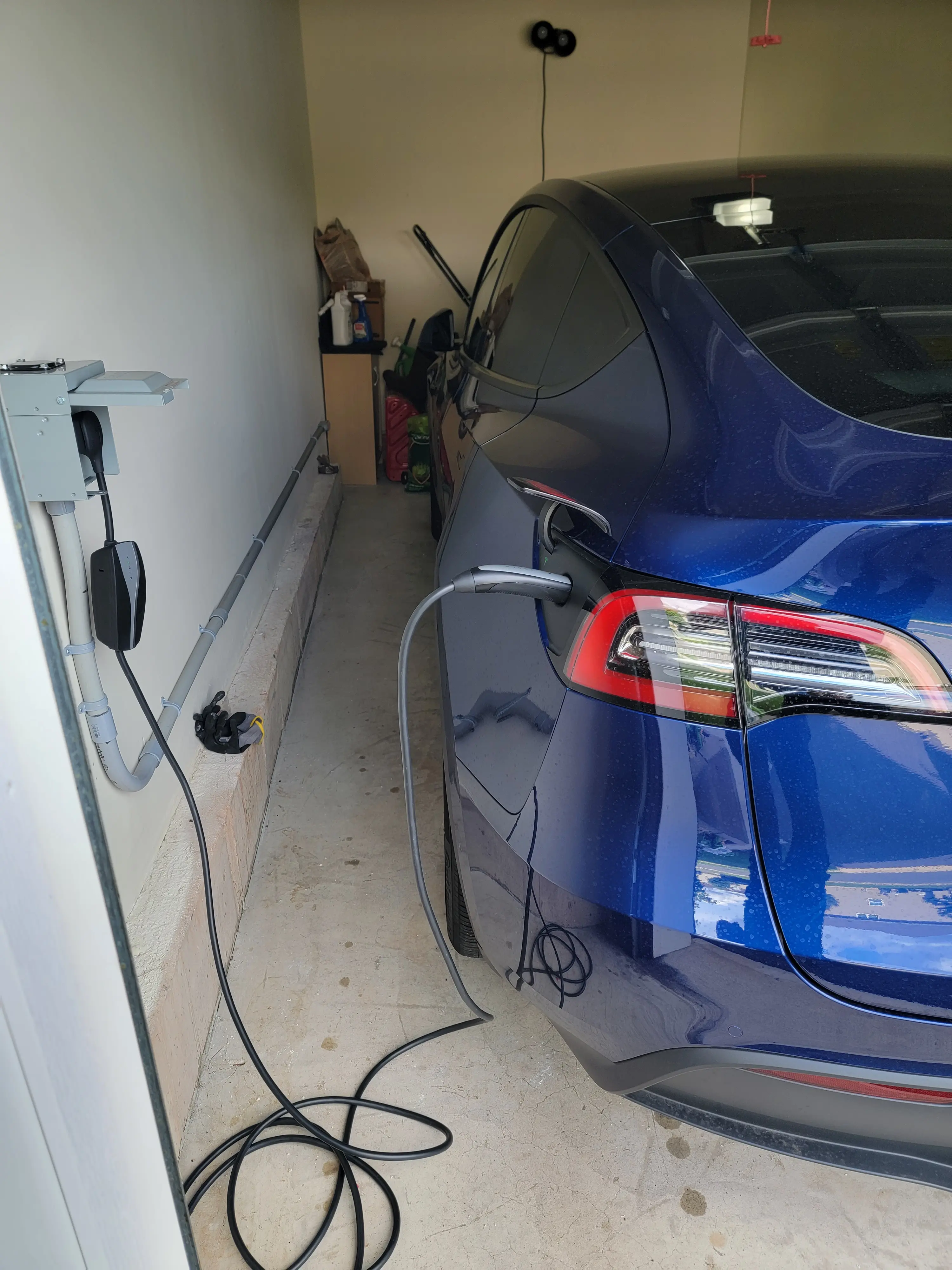 Tesla vehicle charging from a wall-mounted EV charger in a residential garage
