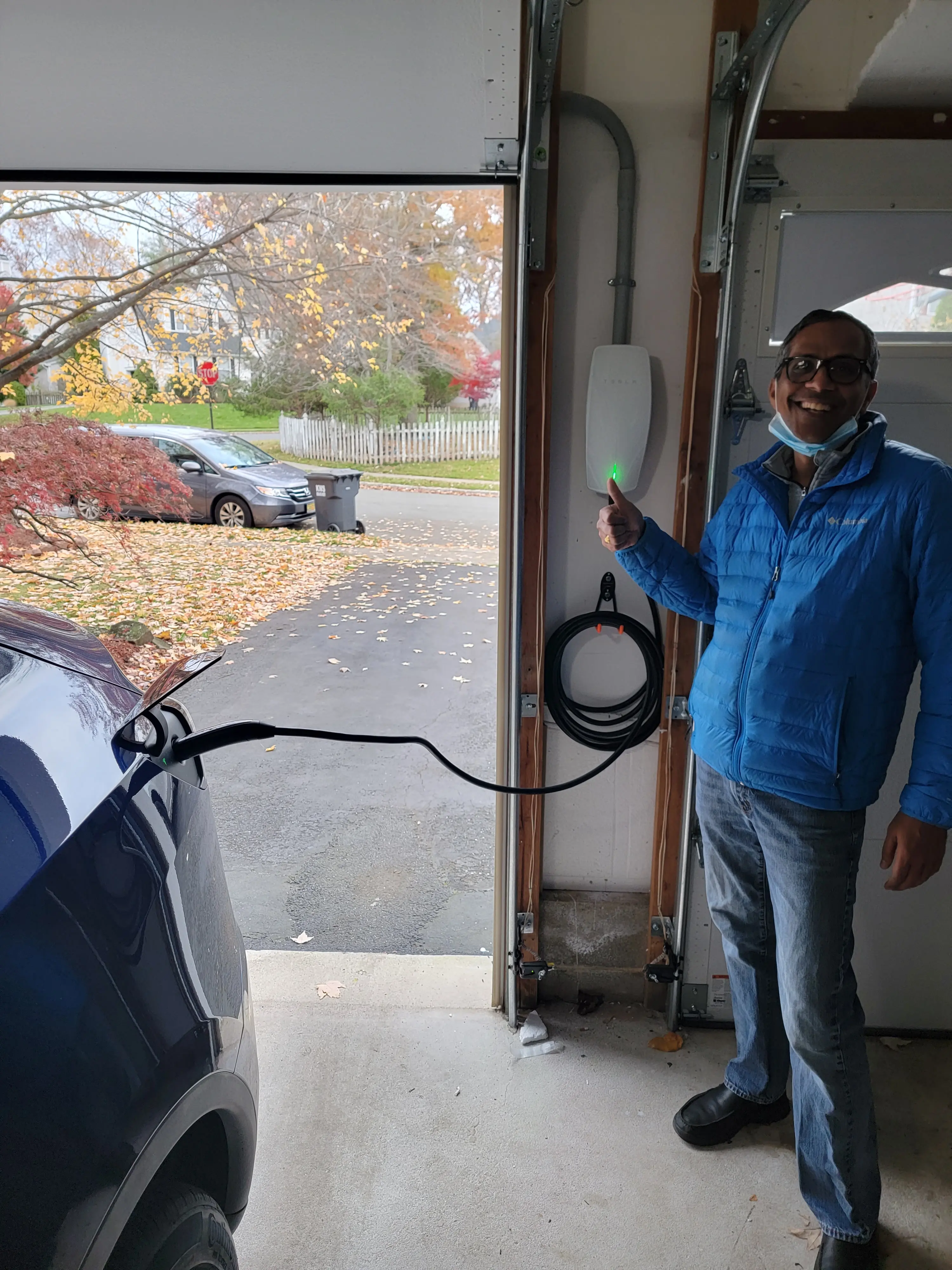 Customer standing beside their Tesla and a newly installed wall-mounted EV charger