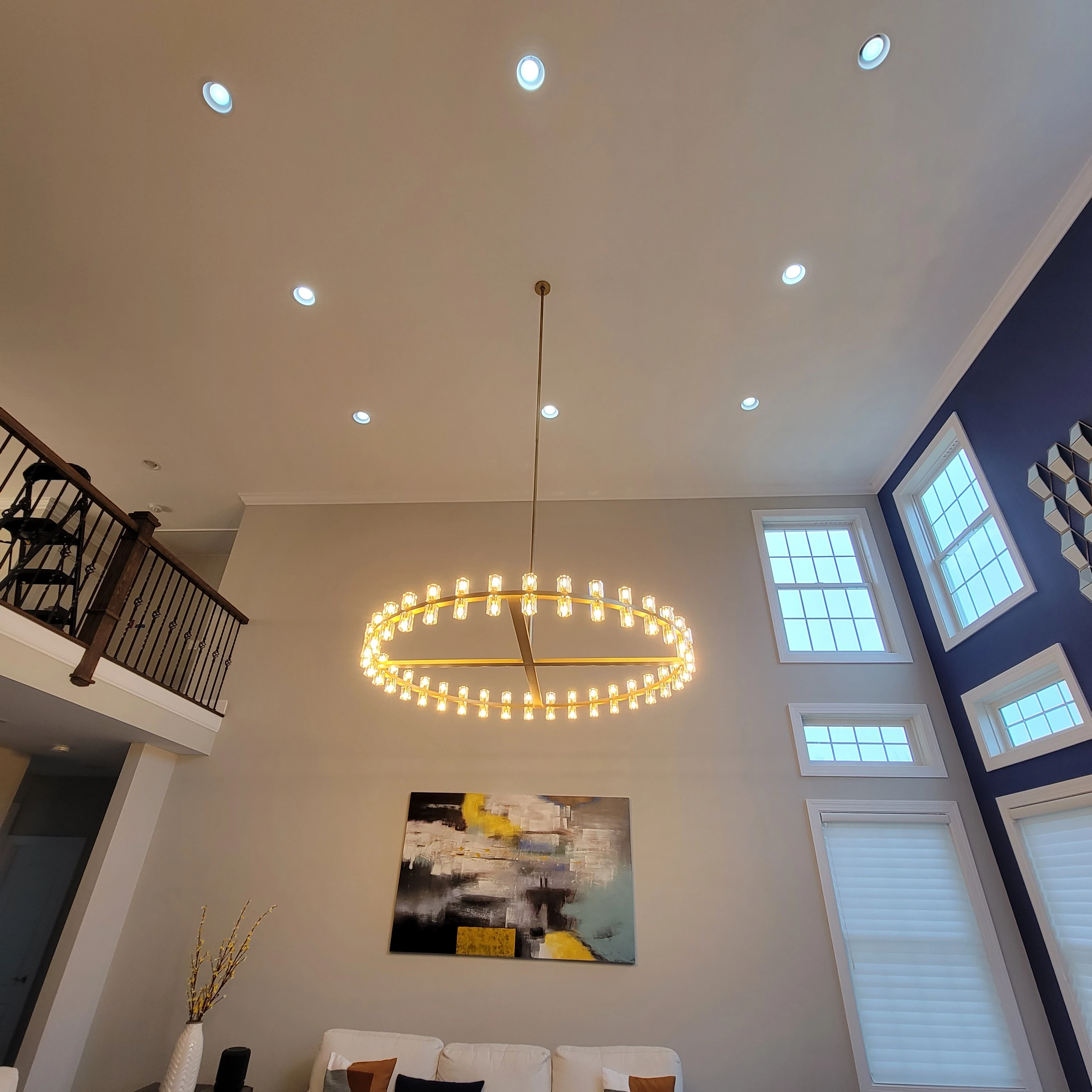 Recessed lighting paired with a chandelier on a high residential ceiling