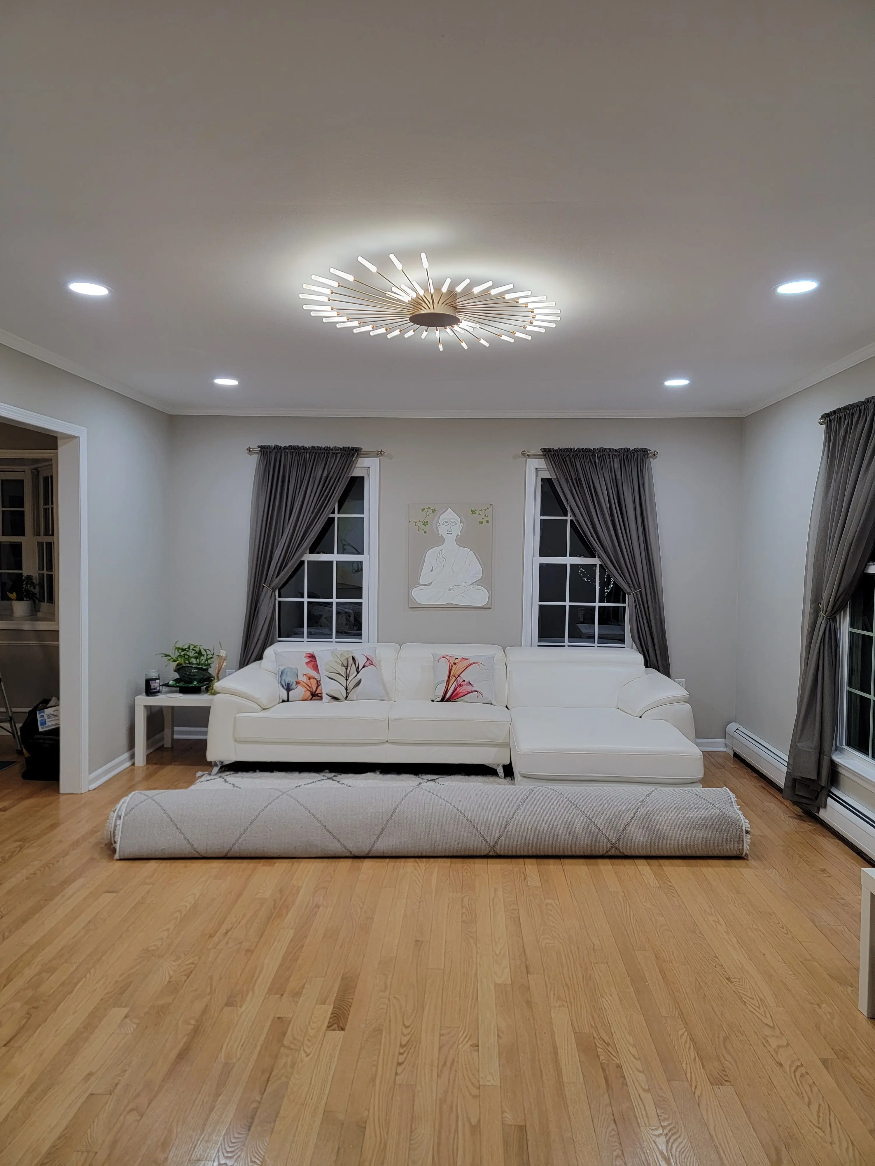 Finished living room with recessed lighting surrounding a decorative central ceiling fixture