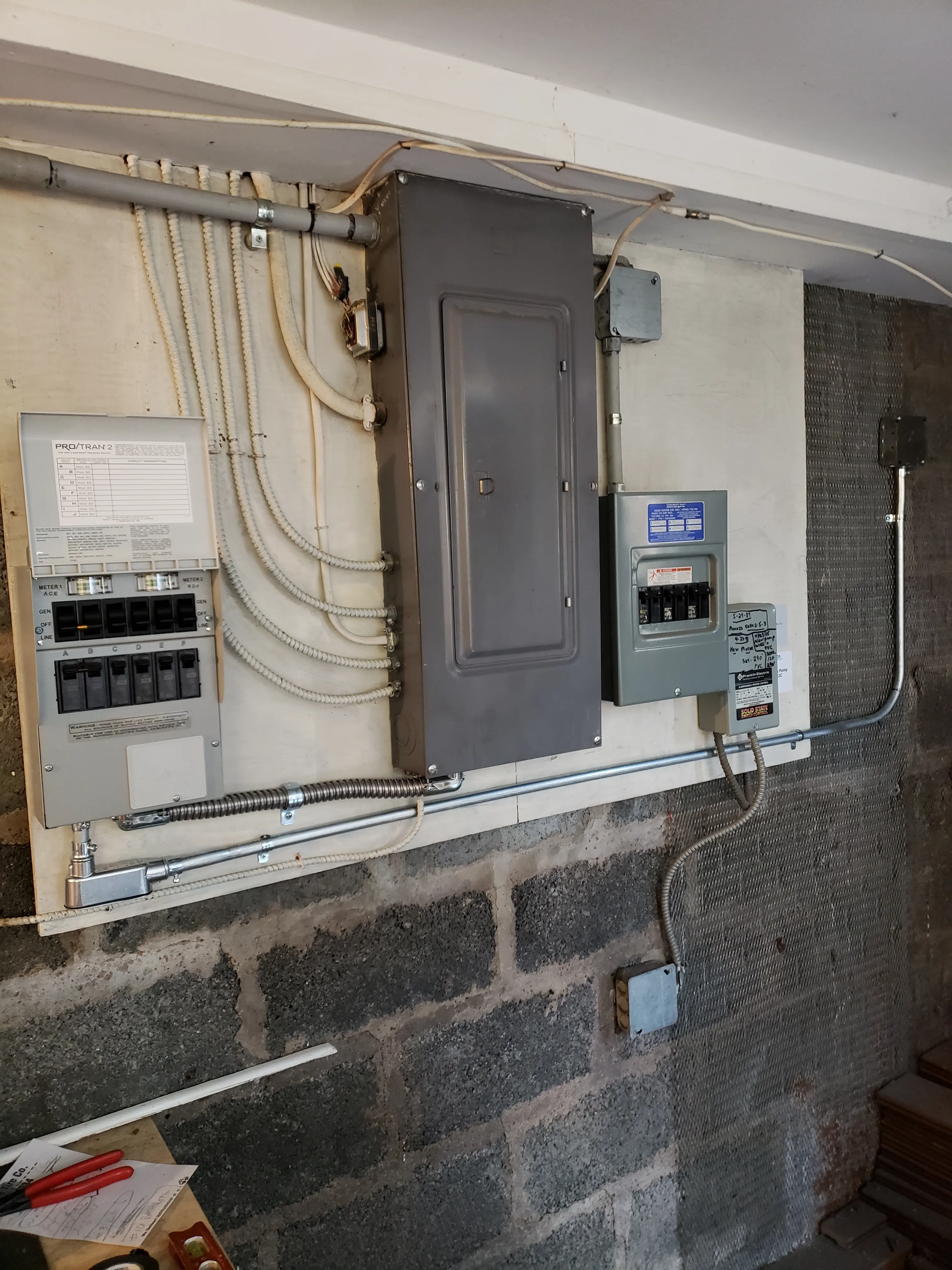 Residential electrical panel, disconnect, and meter mounted on a basement wall