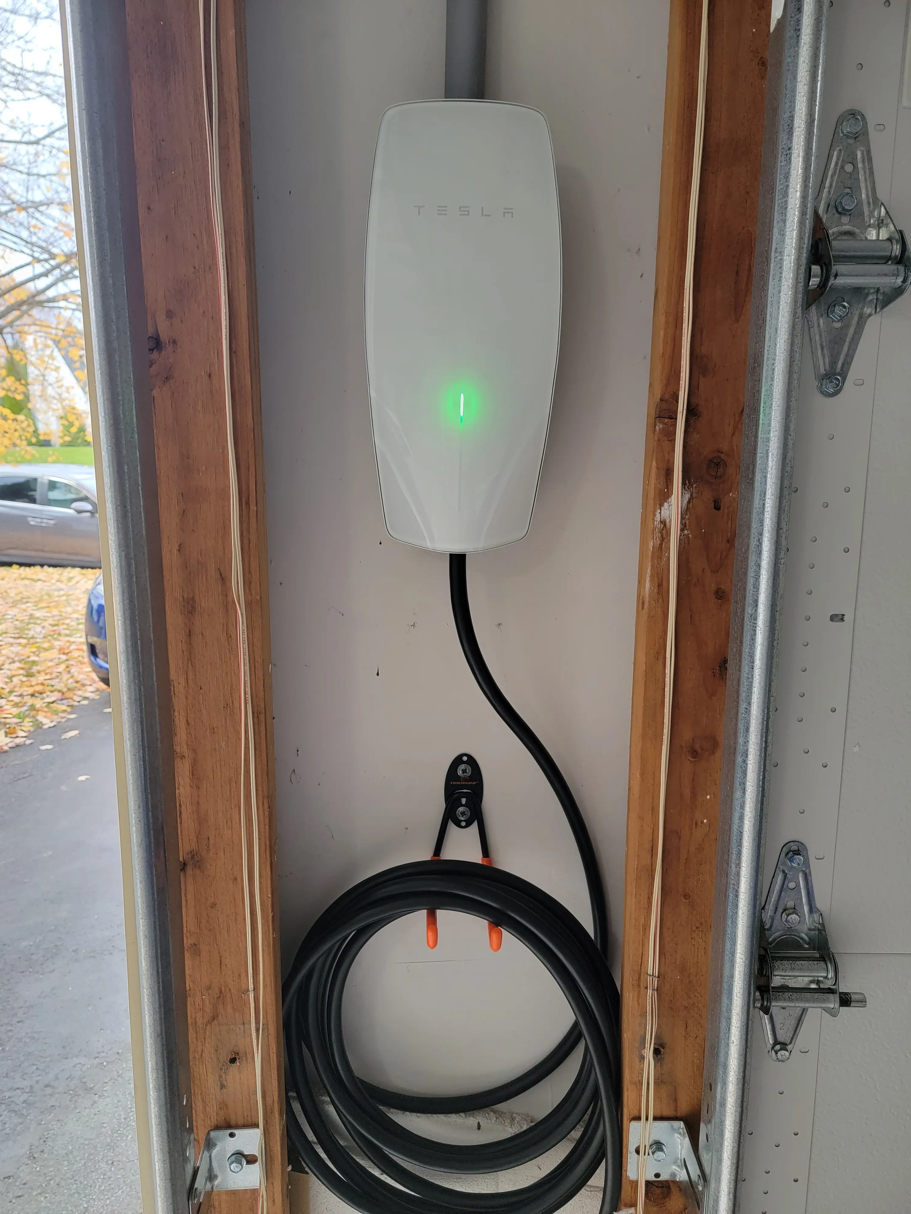 Tesla Wall Connector EV charger mounted in a residential garage with the charging cable coiled
